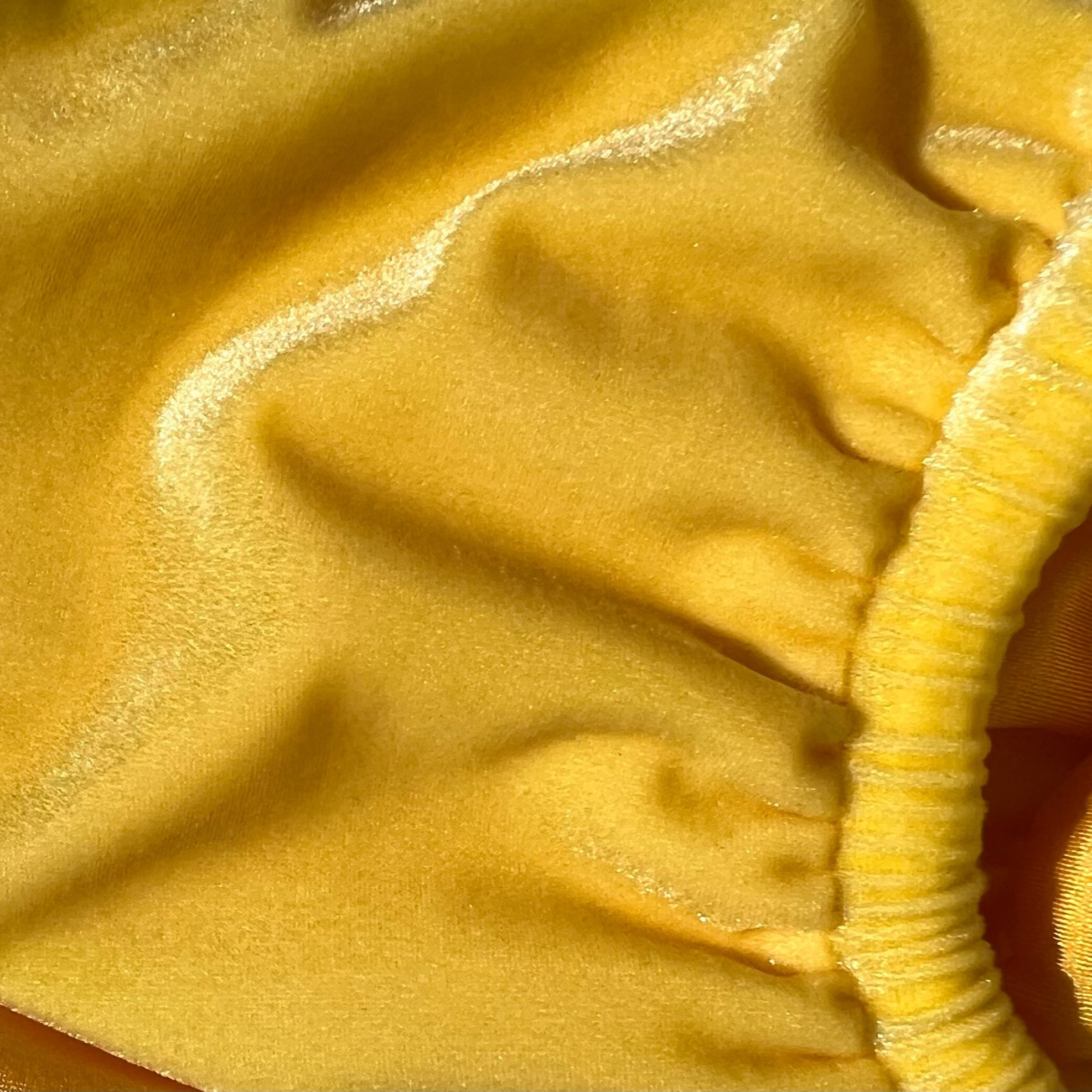 Close up photo of Seduce, a yellow velvet bikini from Baddie Beach Fantasy Collection, showcasing the iridescence of the fabric in the sun.