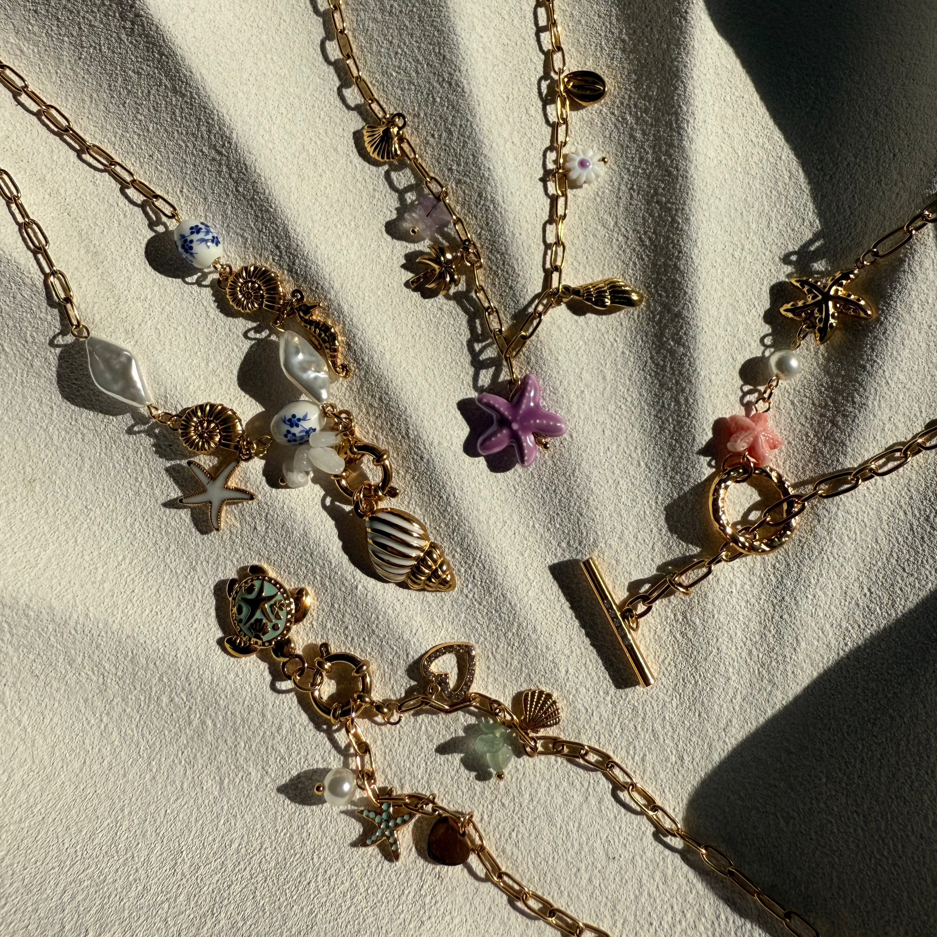Gold necklaces with various charms on a light background