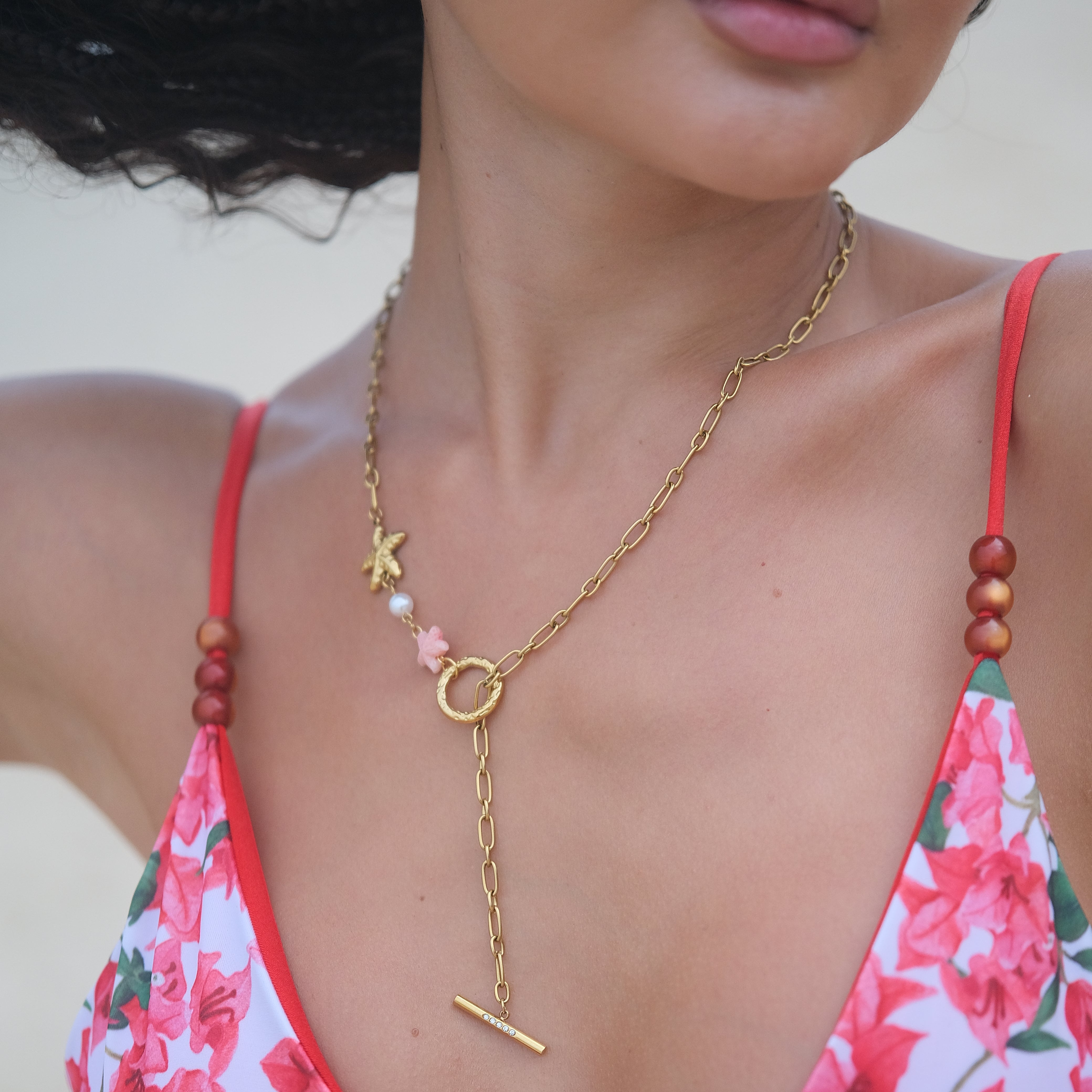 Person wearing a floral bikini with a gold chain necklace.